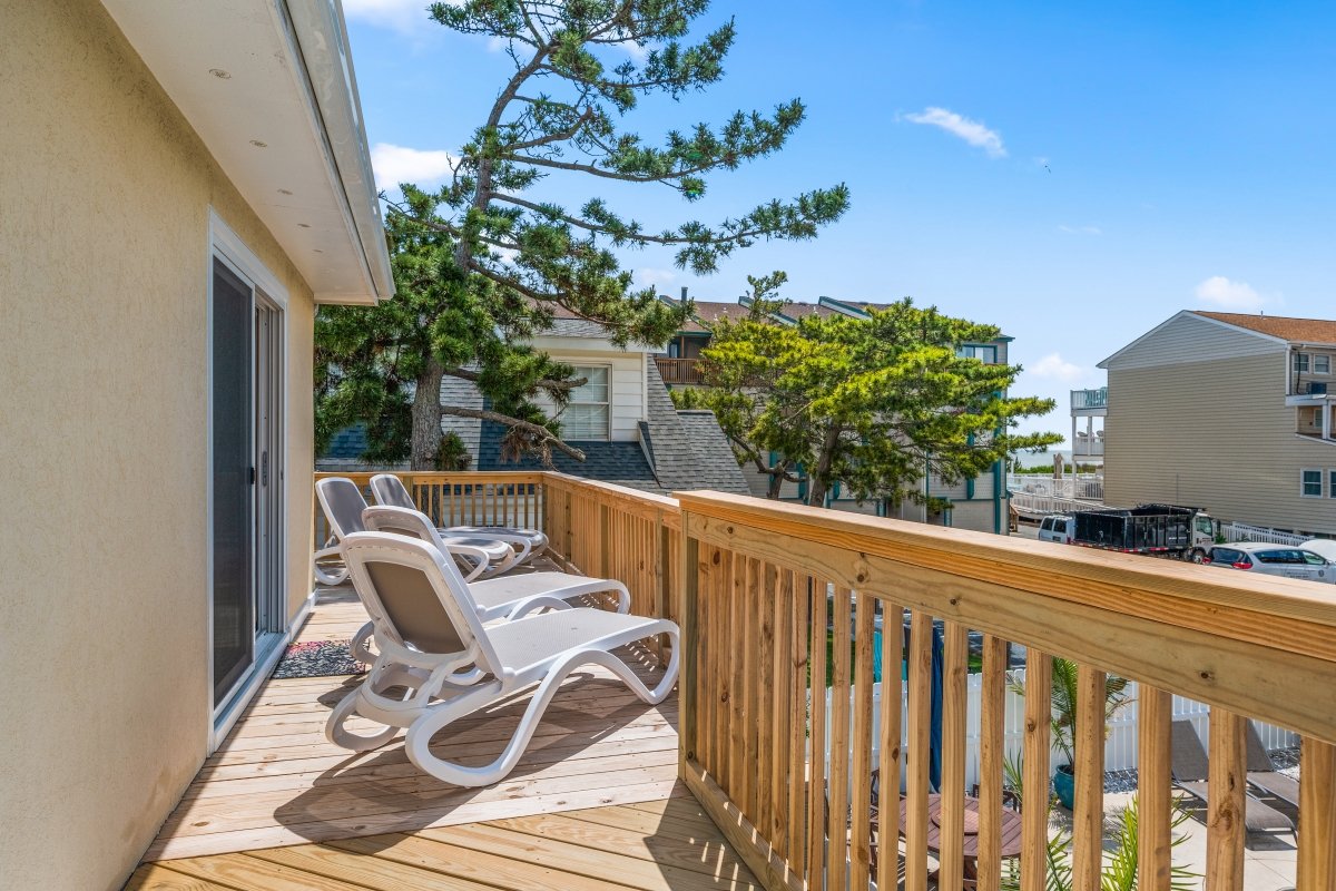 The sun deck attached to the beach house with chairs.