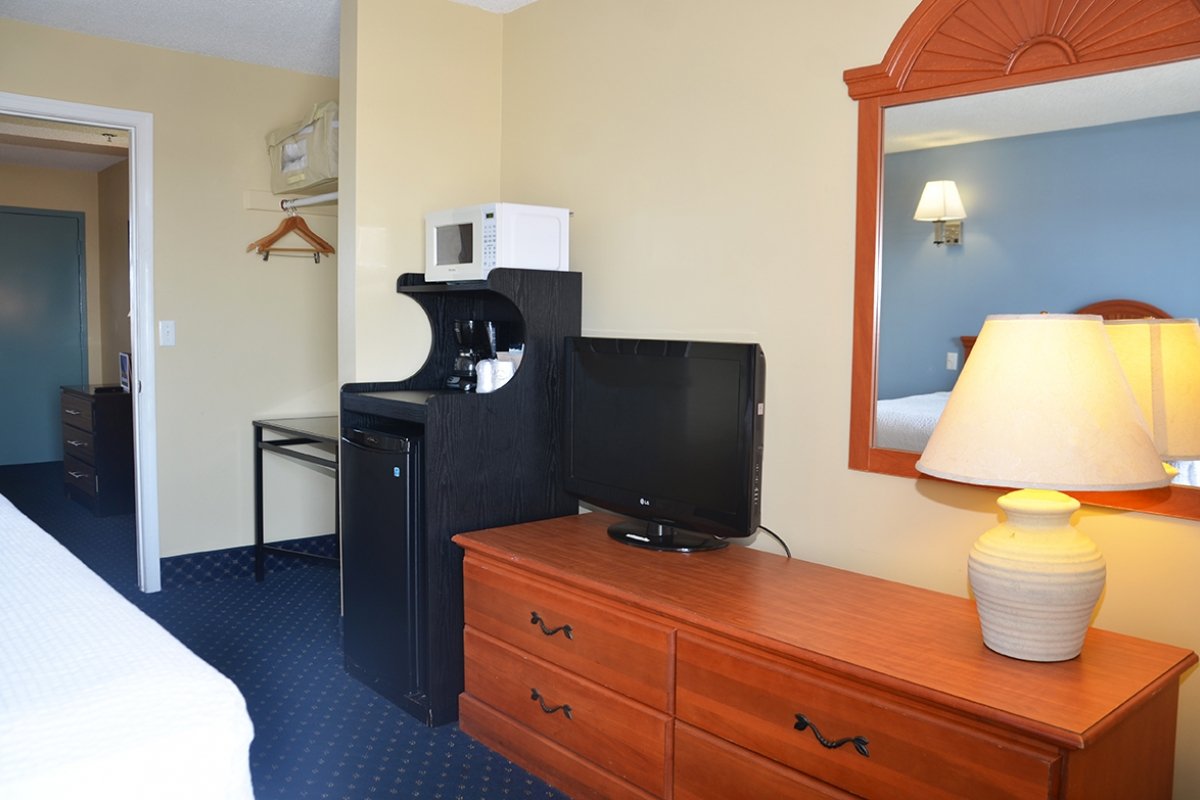 Coastal Palms suite with a tv, dresser, and mini fridge.