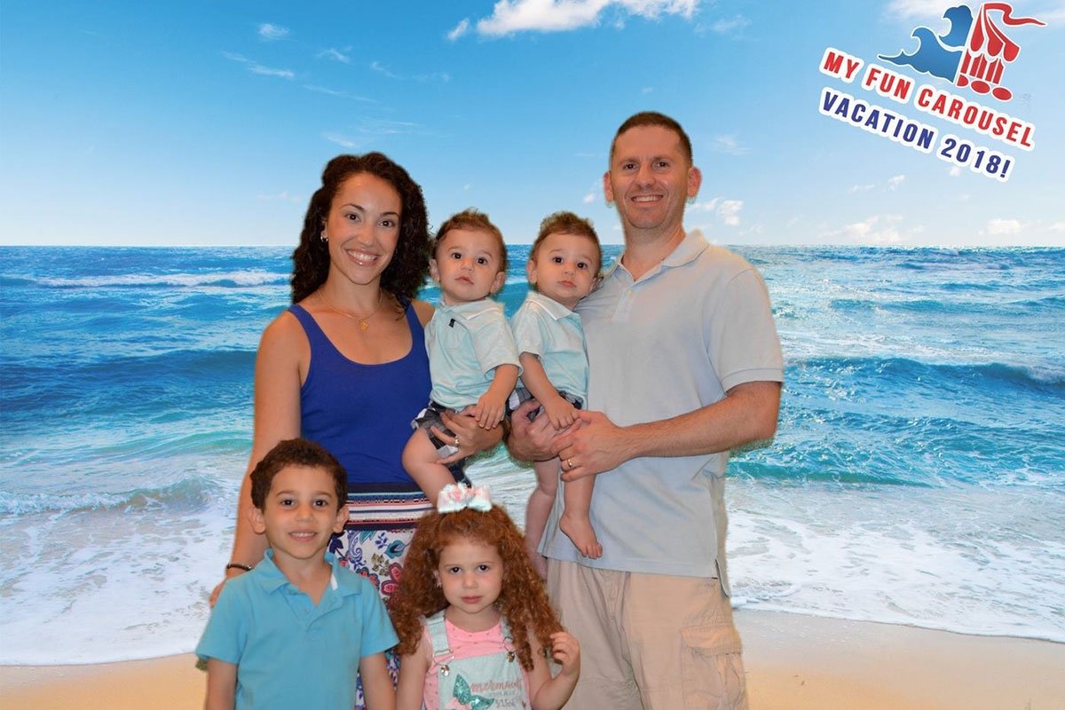 A family of six posing in front of the ocean.