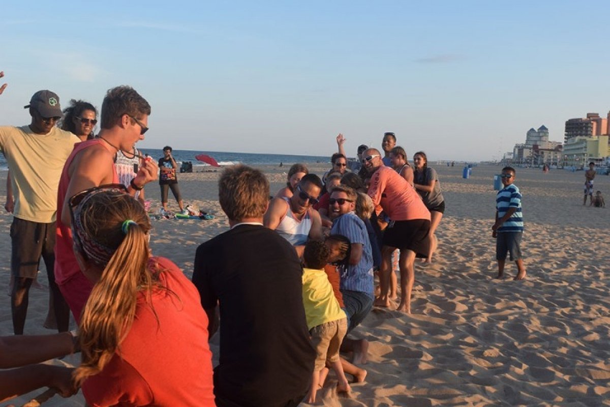 Adults playing tug of war on the beach.