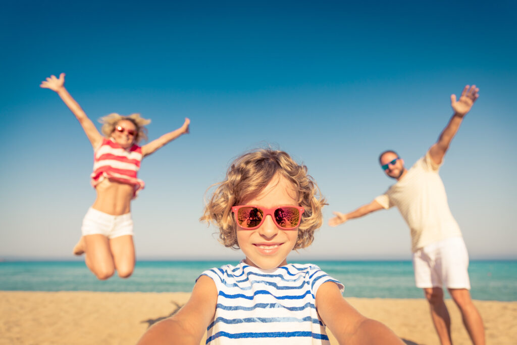 Girl taking a family selfie on the beach.